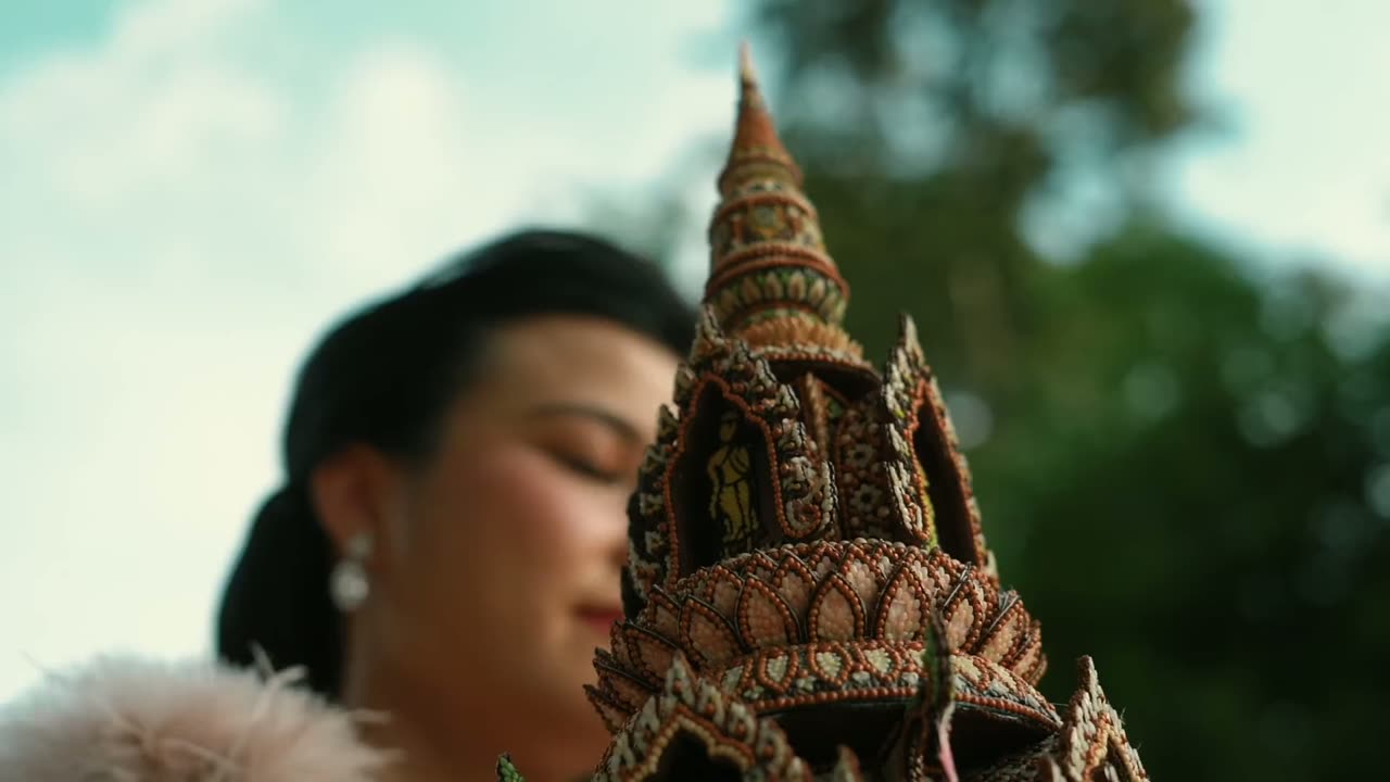 หญิงสาวในชุดไทยยืนคู่กับกระทงทรงปราสาท
