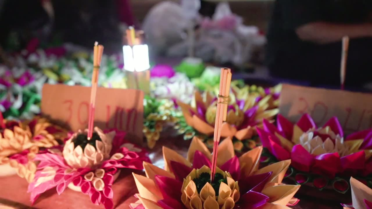 กระทงใบตองและดอกไม้สดวางเรียงขายในตลาด มีป้ายราคาเสียบอยู่
